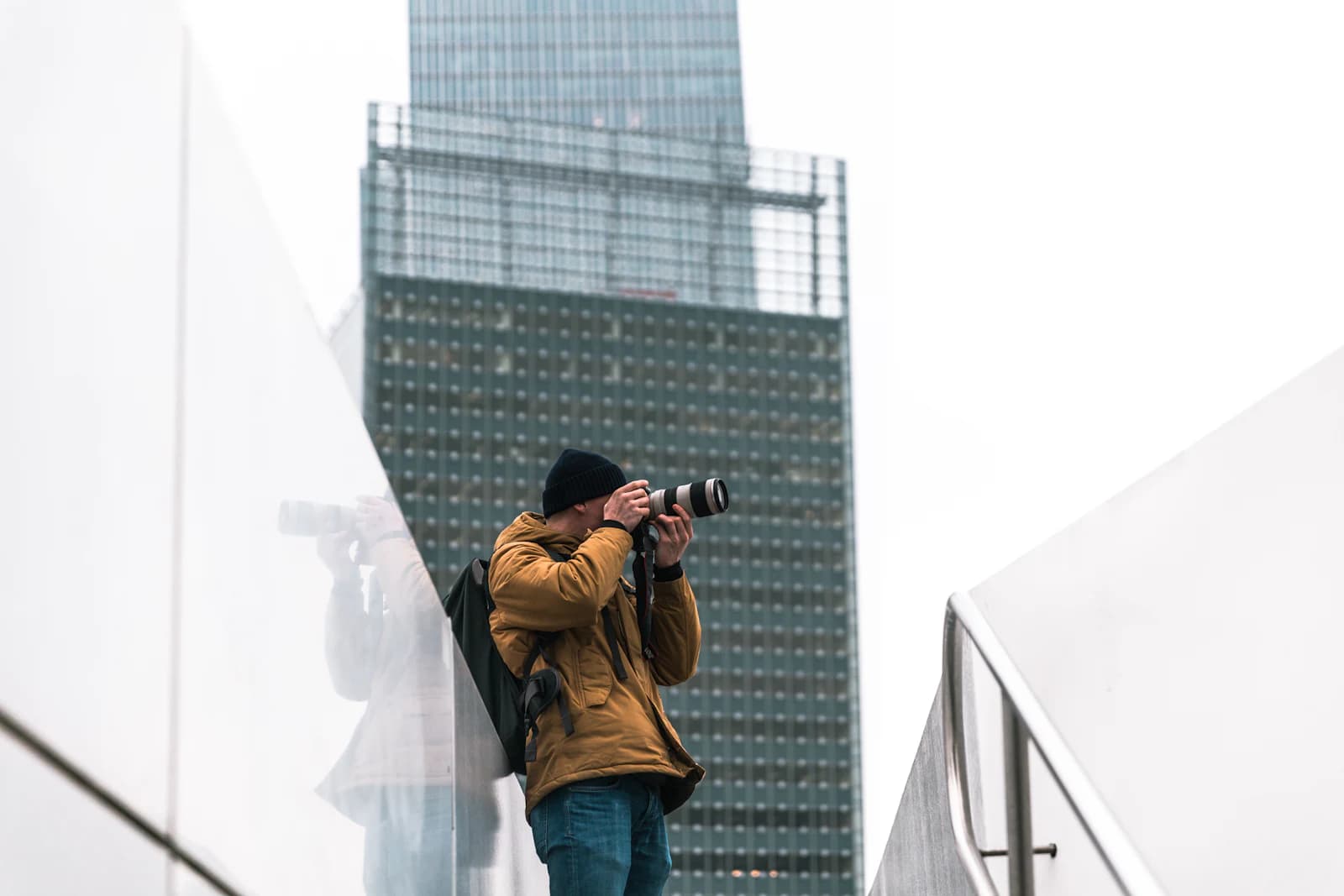 Fotógrafo con cámara y teleobjetivo retratando la fachada de un edificio alto